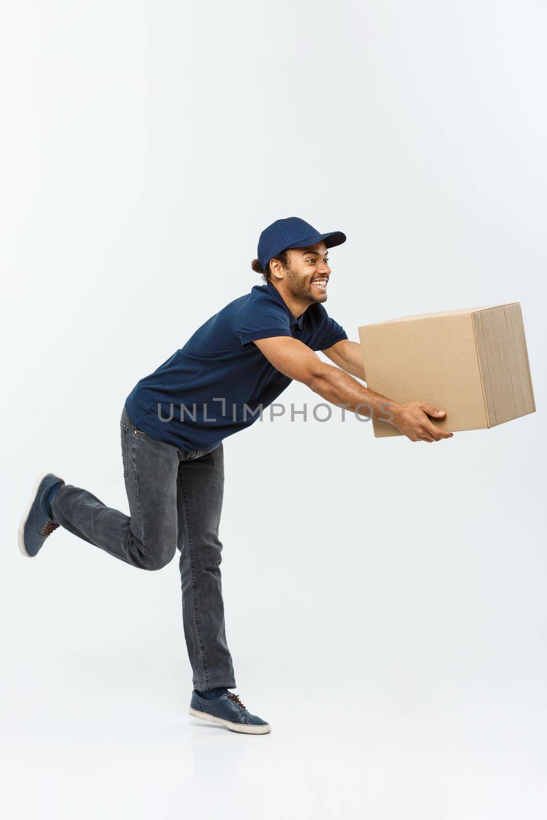 Delivery Concept - Handsome African American delivery man rush running for delivering a package for customer. Isolated on Grey studio Background. Copy Space. by Benzoix