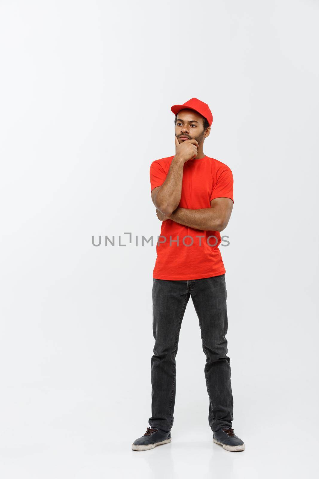 Delivery Concept - Handsome African American delivery man serious thinking of something. Isolated on Grey studio Background. Copy Space