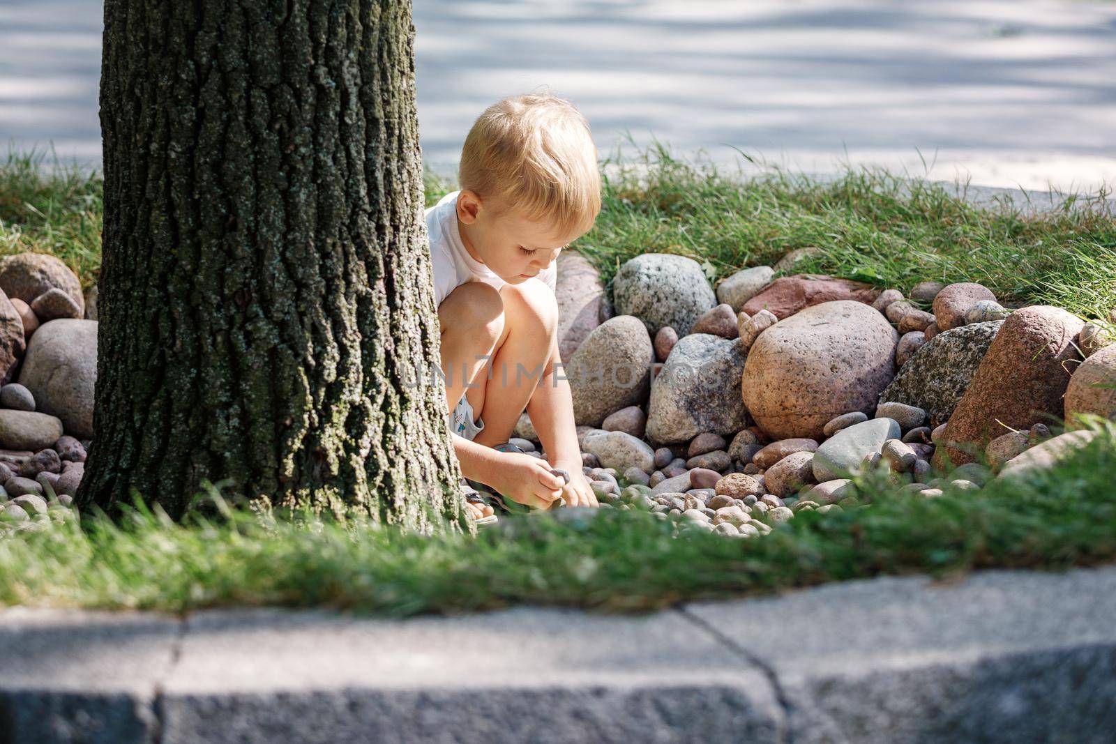 Boy playing in pebble. The concept of recreation, play and the development of children's motor skills. High quality photo. by Lincikas