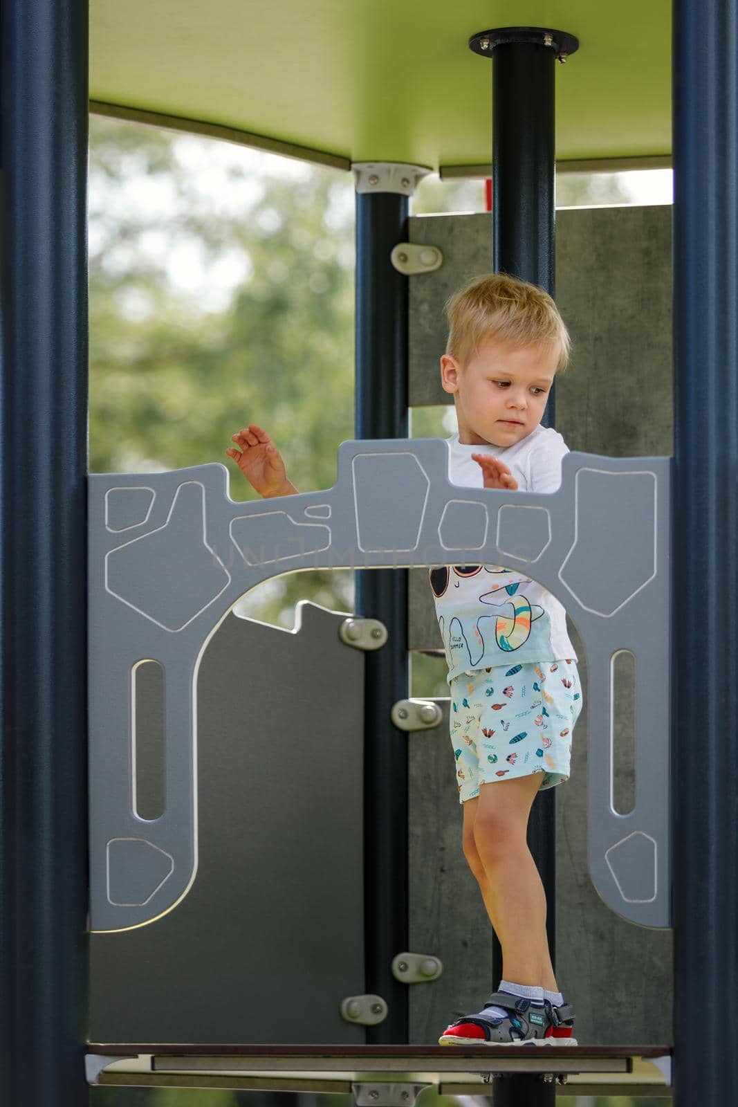 The little boy climbs high up to the playground observation tower.