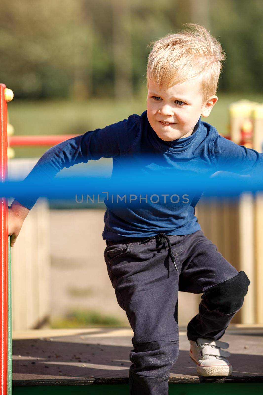 A naughty, very agile boy actively runs through the labyrinths of an outdoor playground by Lincikas