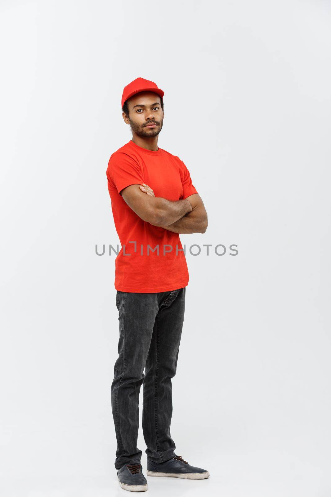 Delivery Concept - Handsome African American delivery man crossed arms over isolated on Grey studio Background. Copy Space. by Benzoix