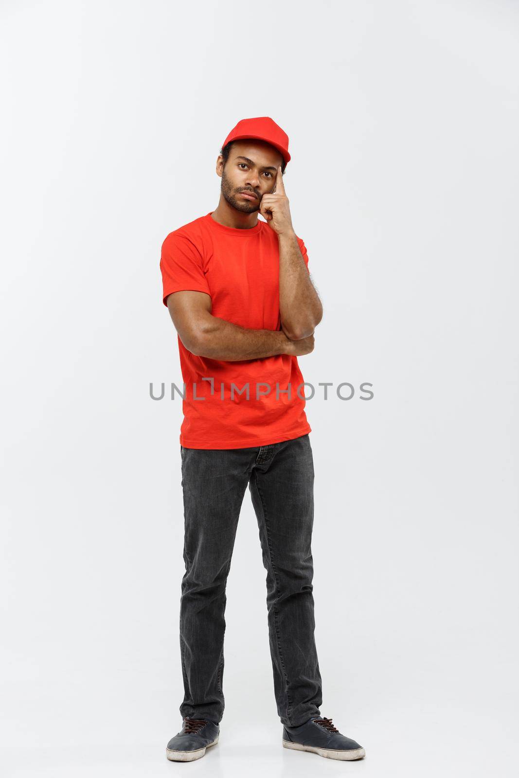 Delivery Concept - Handsome African American delivery man serious thinking of something. Isolated on Grey studio Background. Copy Space