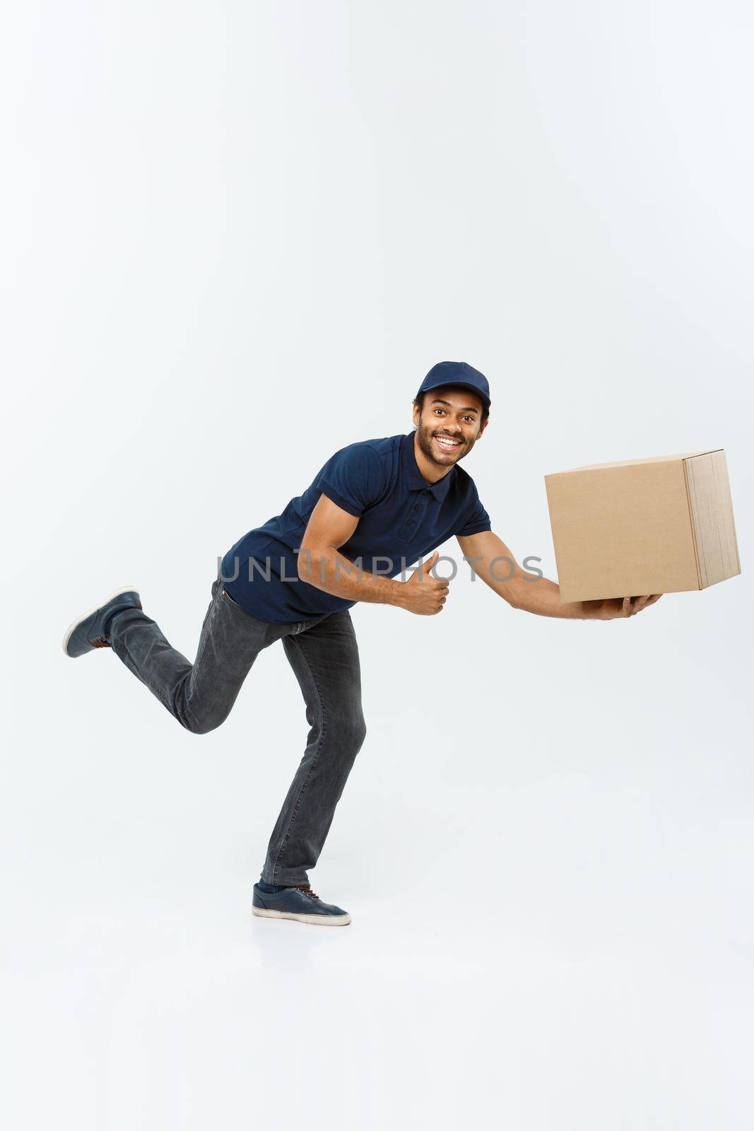 Delivery Concept - Handsome African American delivery man rush running for delivering a package for customer. Isolated on Grey studio Background. Copy Space