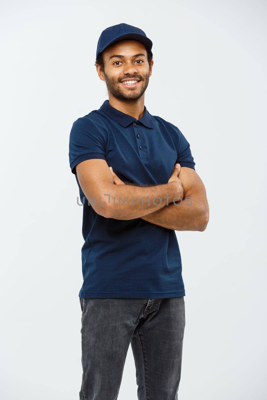 Delivery Concept - Handsome African American delivery man crossed arms over isolated on Grey studio Background. Copy Space