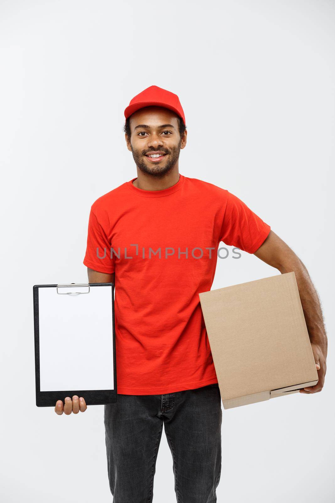 Delivery Concept - Portrait of Handsome African American delivery man or courier showing a confirmation document form to sign. Isolated on Grey studio Background. Copy Space. by Benzoix