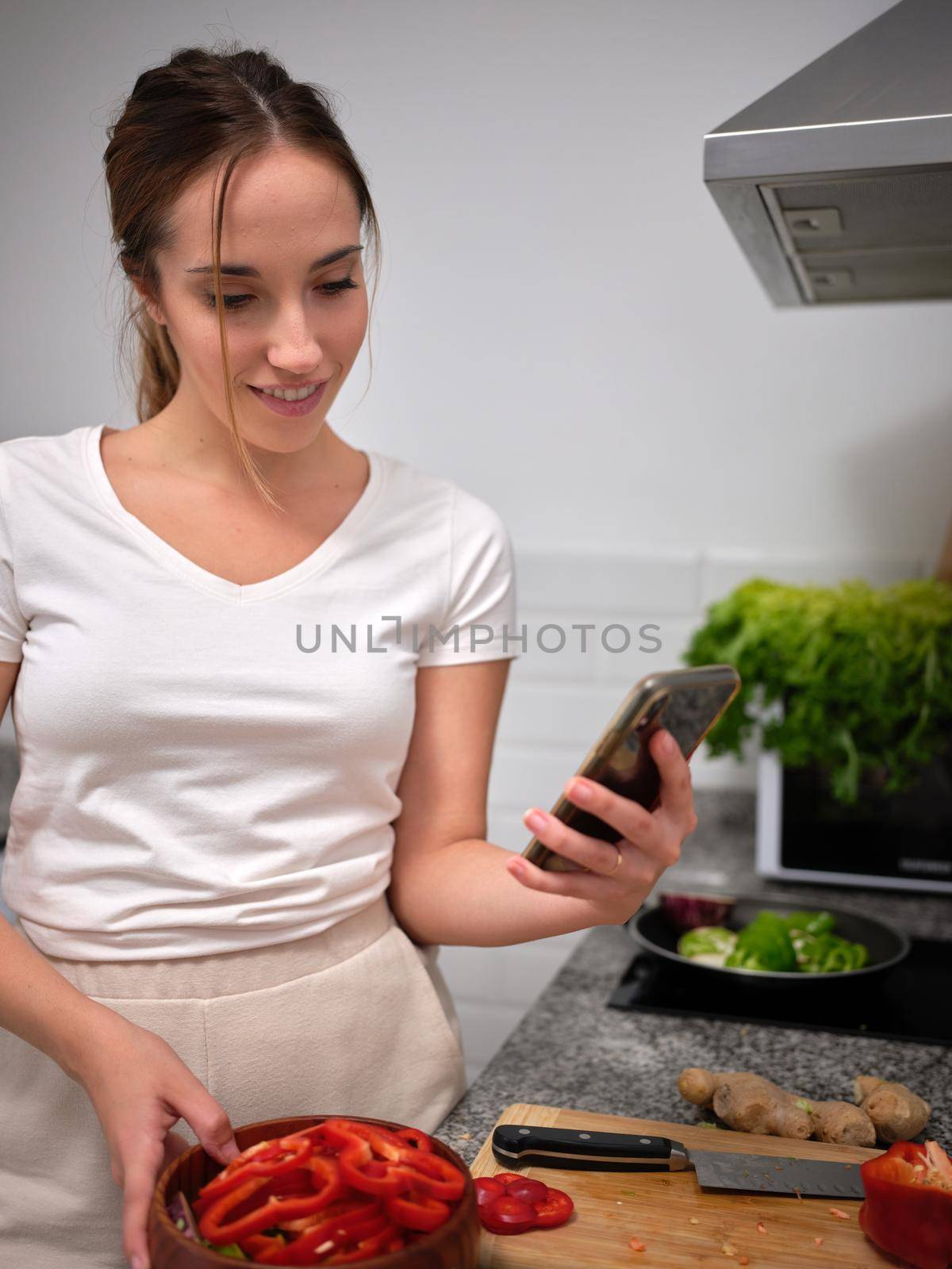 woman revising the tabbouleh recipe on the phone before moving on to the next step, vertical close up