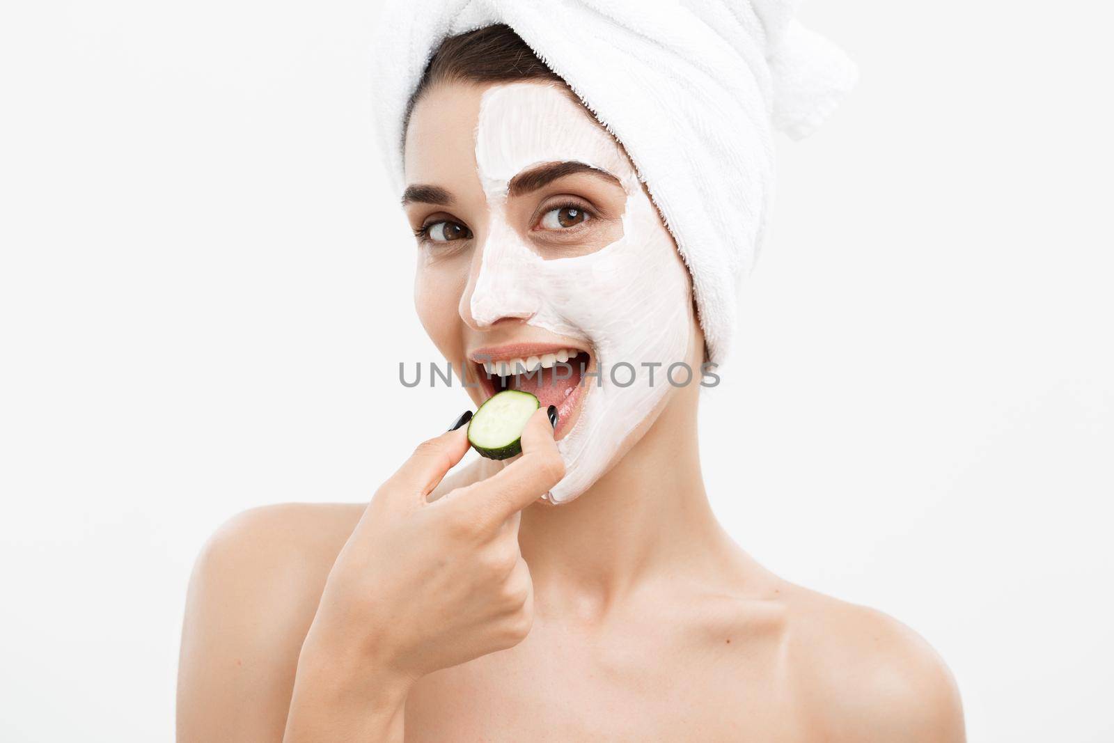 Beauty Youth Skin Care Concept - Portrait Beautiful Caucasian Woman apply cream and holding fresh cucumber in front of her face.Isolated over white background