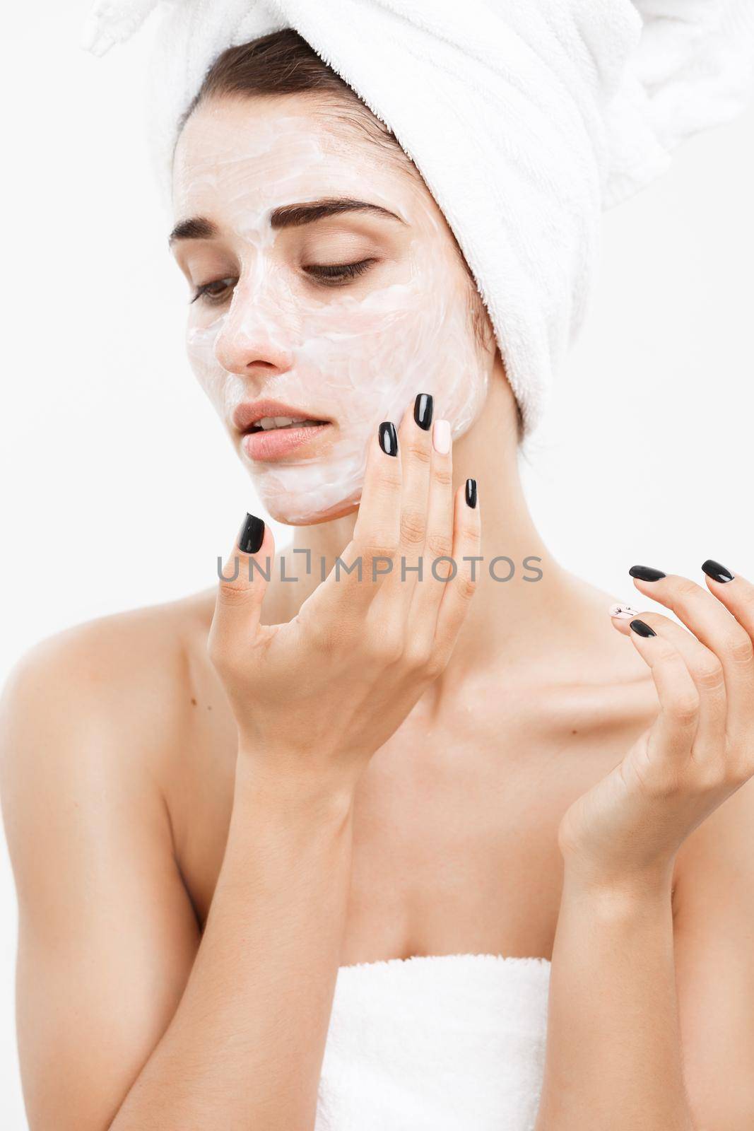 Beauty Skin Care Concept - Beautiful Caucasian Woman Face Portrait applying cream mask on her facial skin white background. by Benzoix