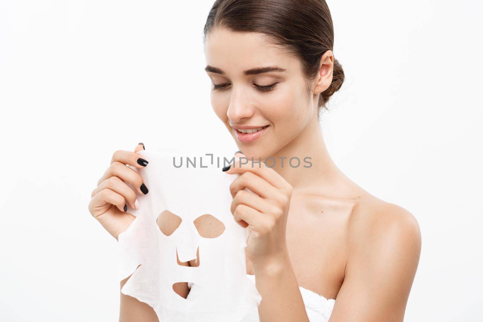 Beauty Skin Care Concept - Beautiful Caucasian Woman applying paper sheet mask on her face white background. by Benzoix