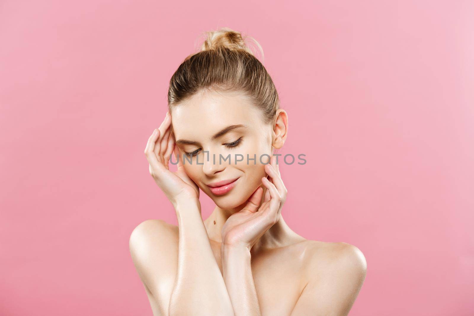 Beauty Spa Concept - Caucasian Woman with perfect face skin Portrait. Beautiful Brunette Spa Girl showing empty copy space. Isolated on pink studio background. Proposing a product. by Benzoix