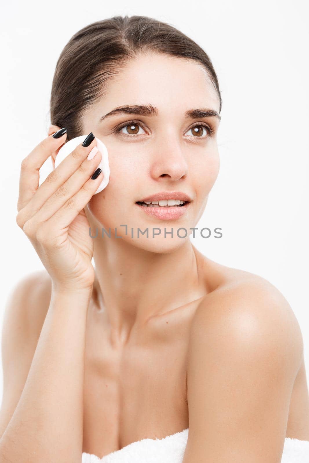 Beauty Skin Care Concept - Beautiful woman cleaning her face with cotton swab - over white background and smiling. by Benzoix