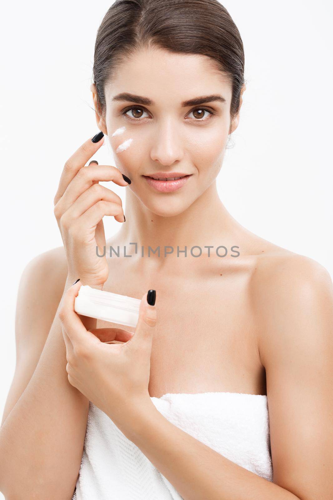 Beauty Youth Skin Care Concept - Close up Beautiful Caucasian Woman Face Portrait applying some cream to her face. Beautiful Spa model Girl with Perfect Fresh Clean Skin over white background