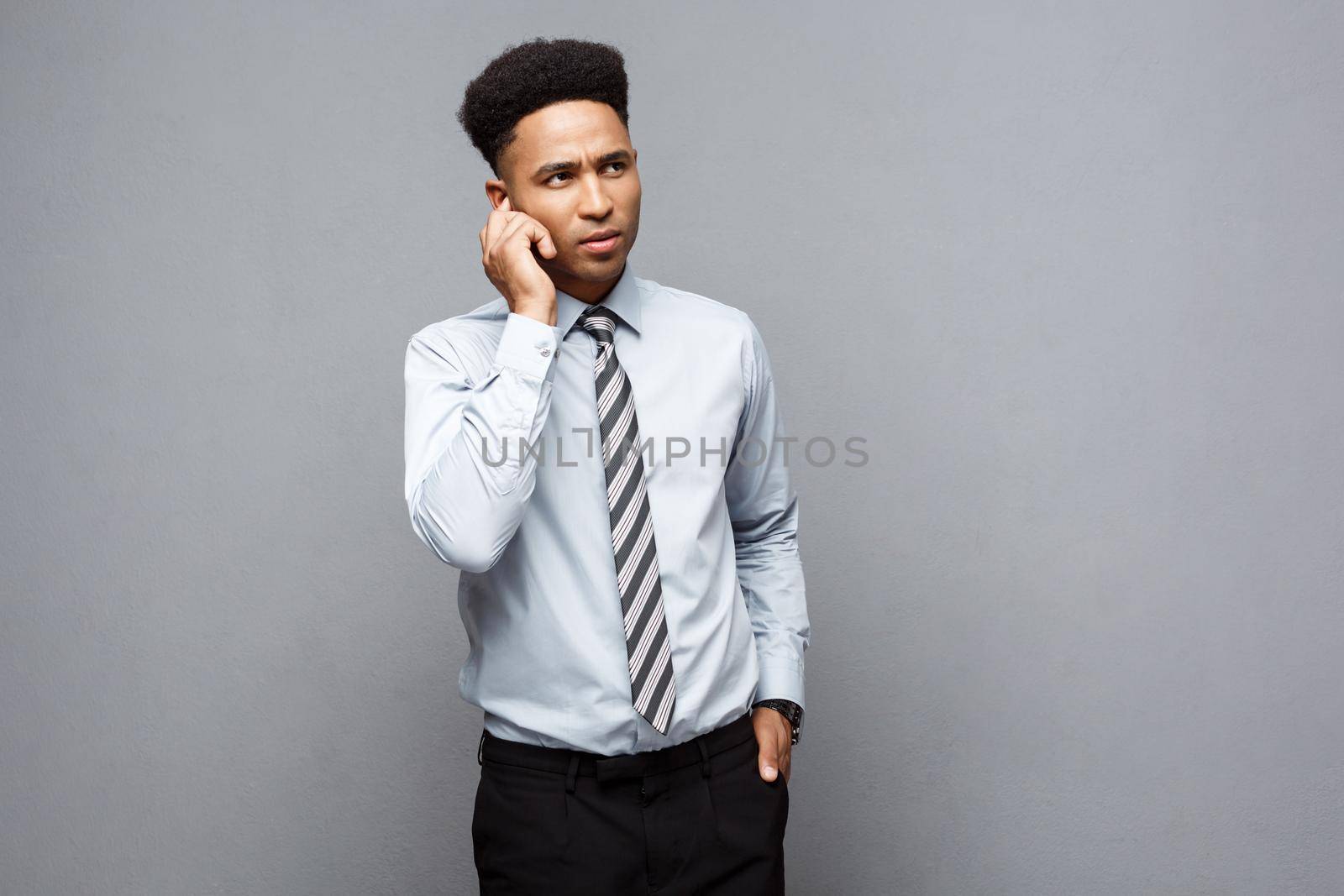 Business Concept - Confident thoughtful young African American holding hand on his chin and thinking about business. by Benzoix
