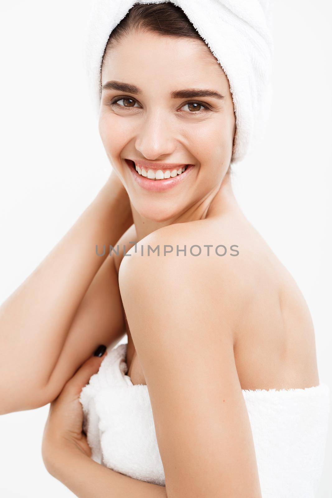 Beauty and Skin care concept - Beautiful caucasian Young Woman with bath towel on head covering her breasts, on white touching her skin. by Benzoix