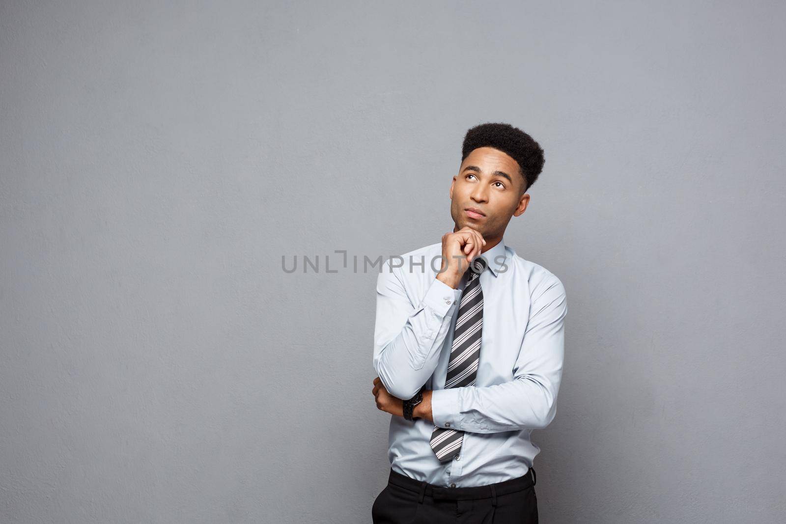 Business Concept - Confident thoughtful young African American holding hand on his chin and thinking about business. by Benzoix