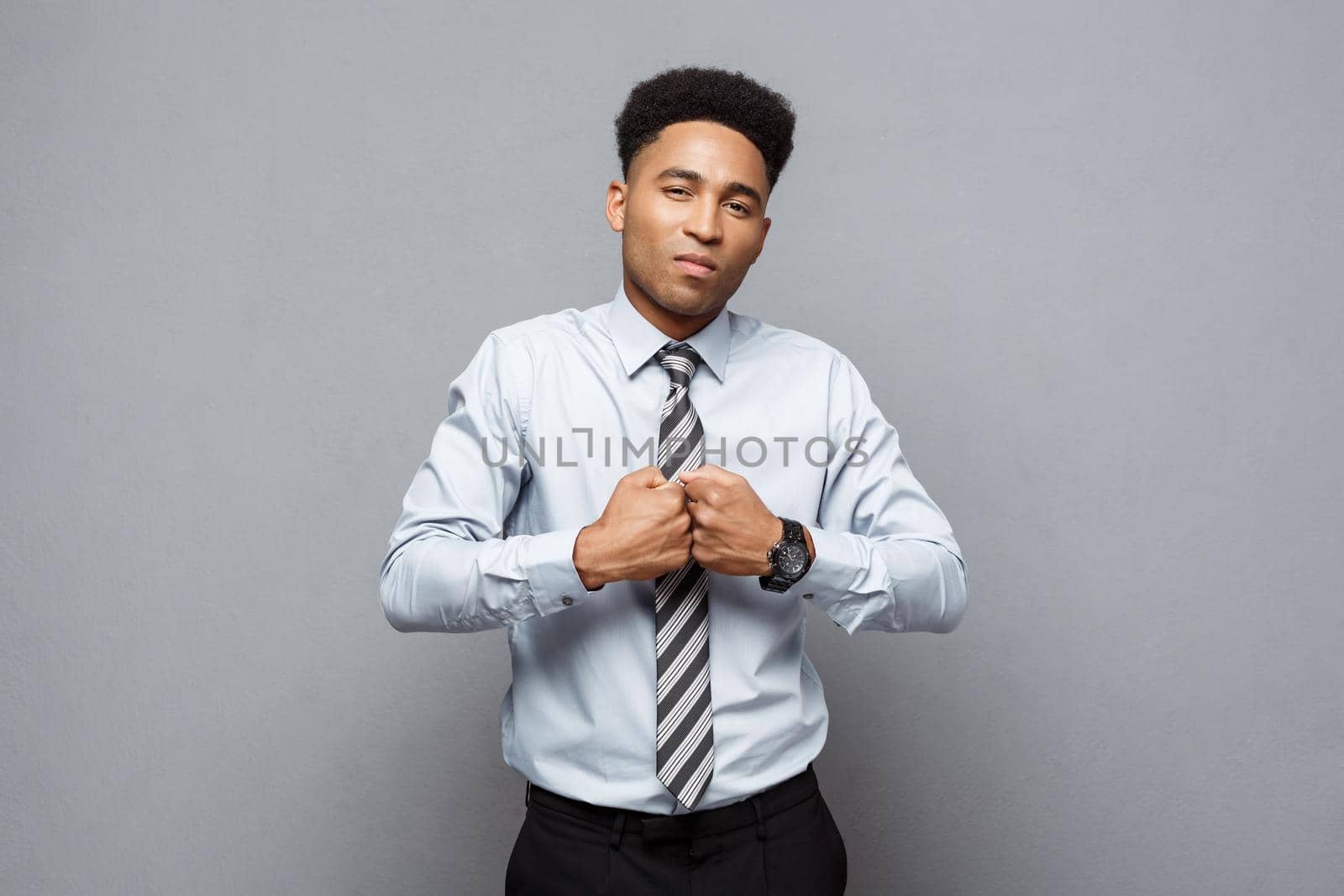 Business Concept - Confident cheerful young African American in boxing poseture over grey background