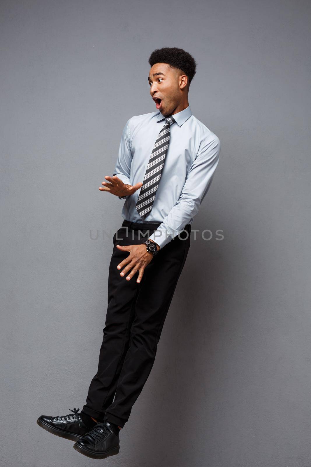 Business Concept - Full length portrait of successful african american businessman surprising jump in the office