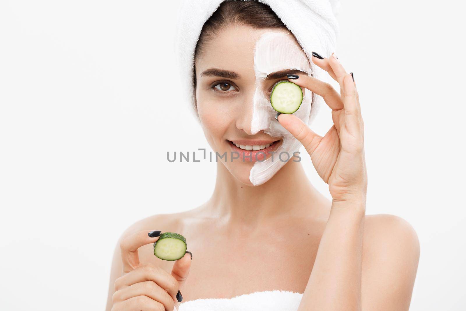 Beauty Youth Skin Care Concept - Portrait Beautiful Caucasian Woman apply cream and holding fresh cucumber in front of her face.Isolated over white background