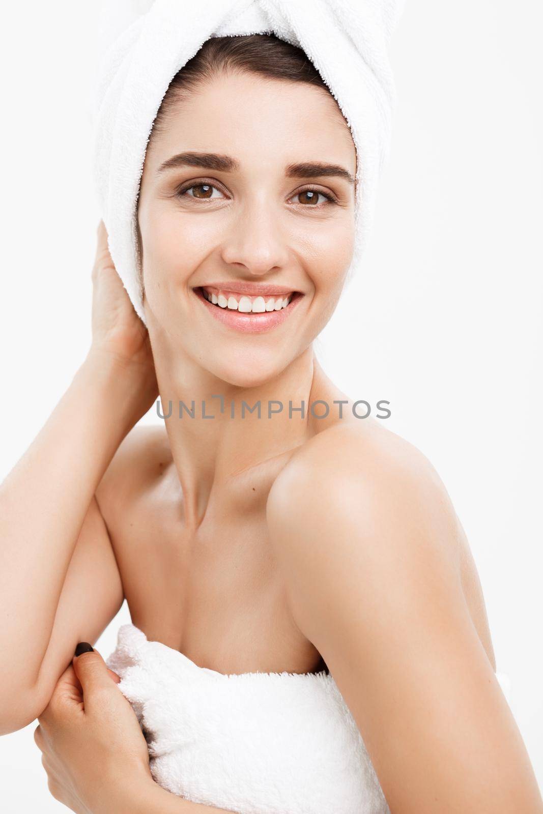 Beauty and Skin care concept - Beautiful caucasian Young Woman with bath towel on head covering her breasts, on white touching her skin