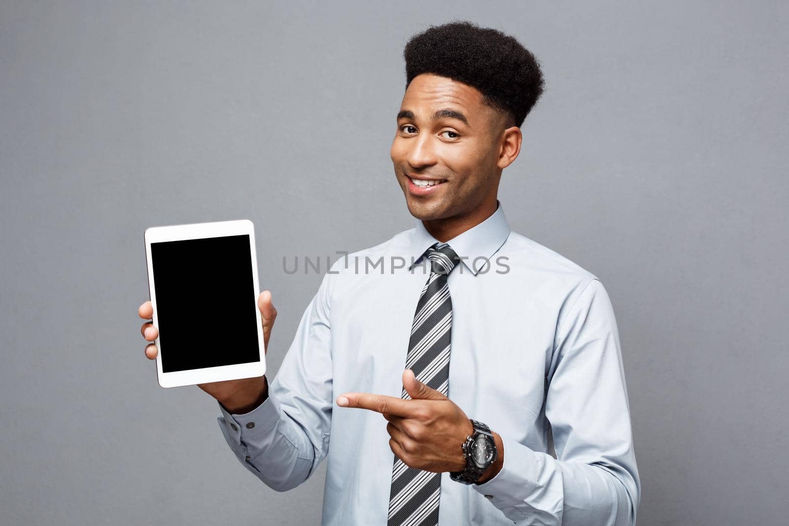 Business Concept - Happy handsome professional african american businessman showing digital tablet to client