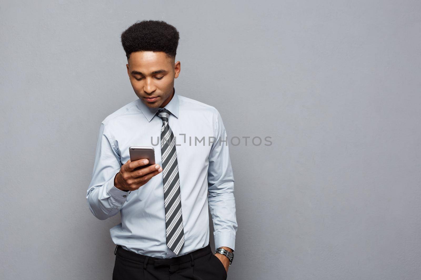 Business Concept - Happy handsome professional african american businessman texting on mobile phone