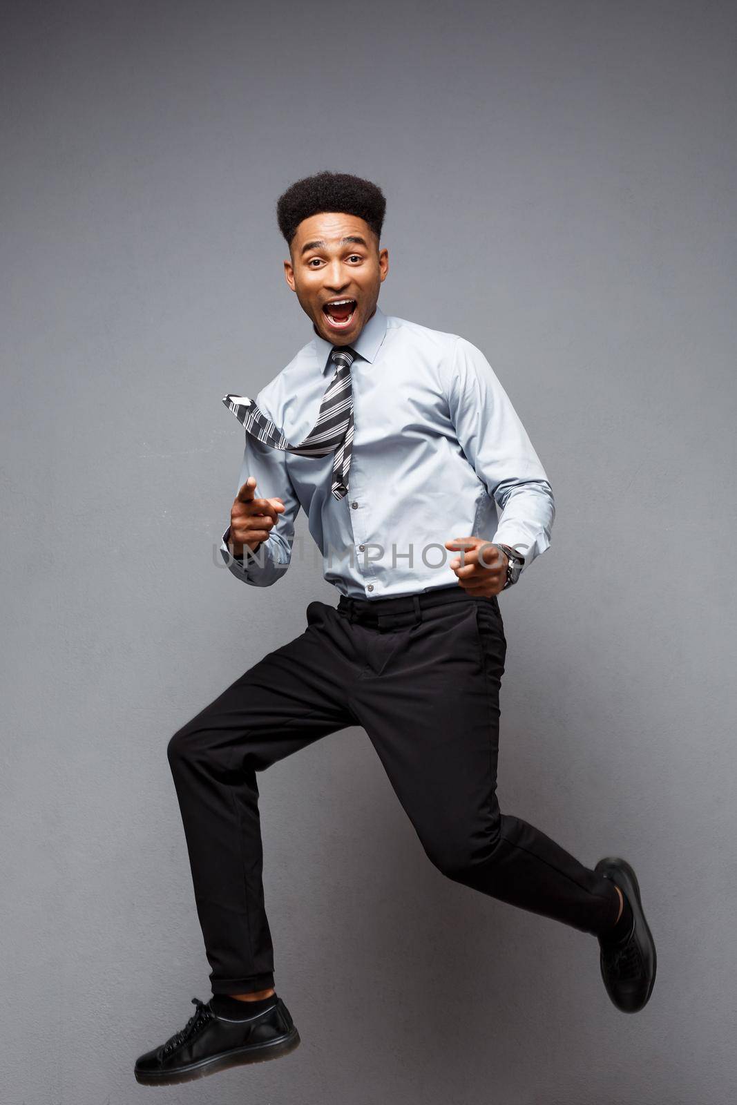 Business Concept - Full length portrait of successful african american businessman happy jumping in the office. by Benzoix