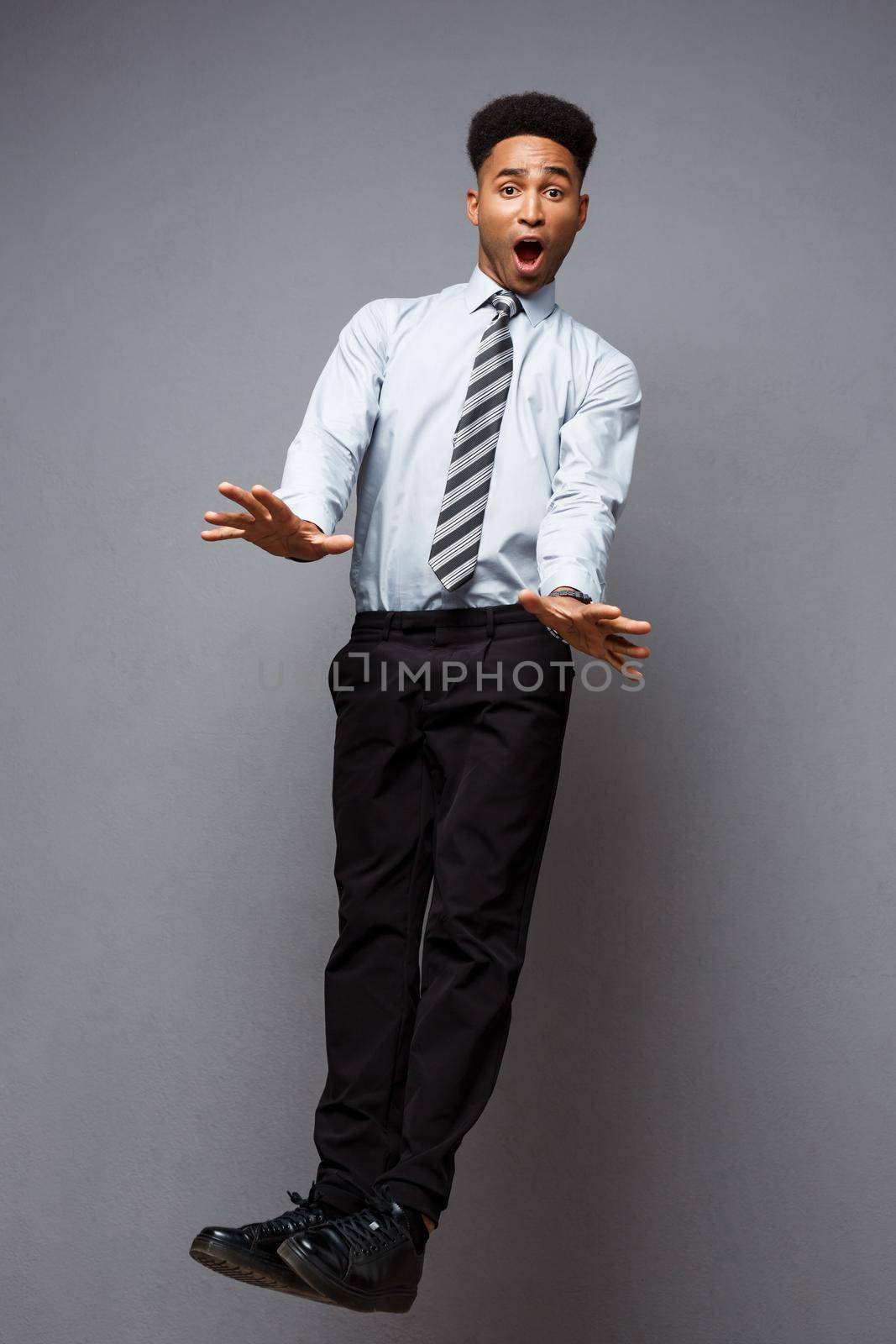 Business Concept - Full length portrait of successful african american businessman surprising jump in the office. by Benzoix