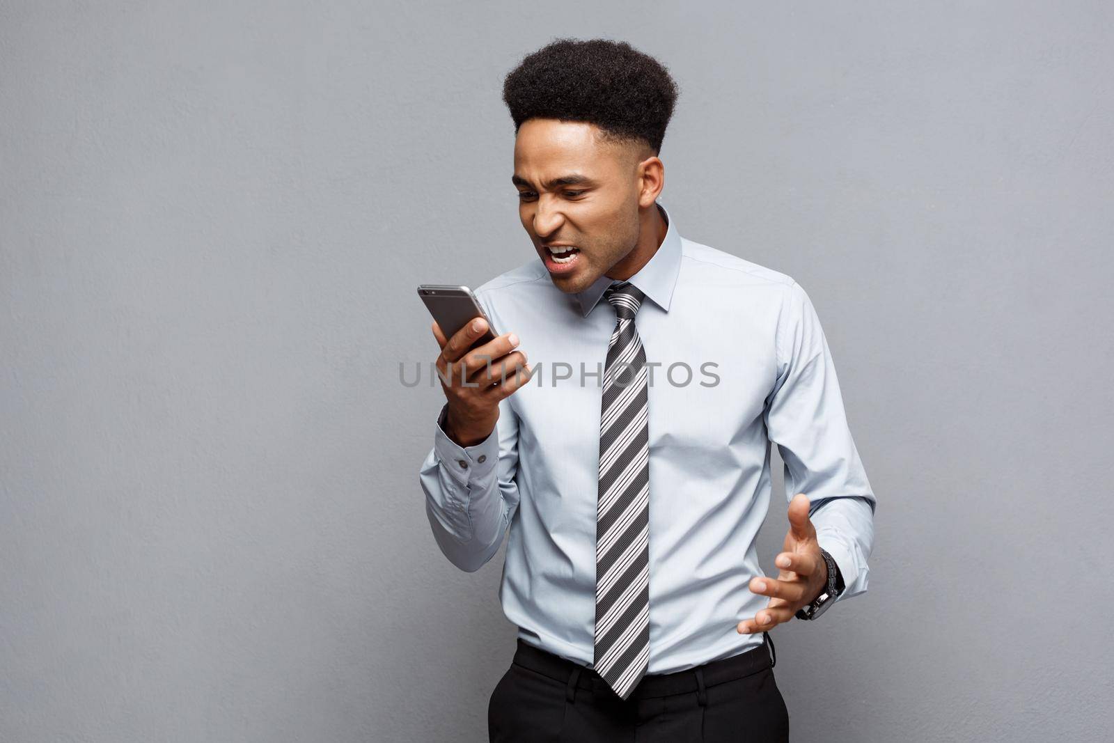 Business Concept - Stressful african american businessman shouting and screaming on mobile phone. by Benzoix