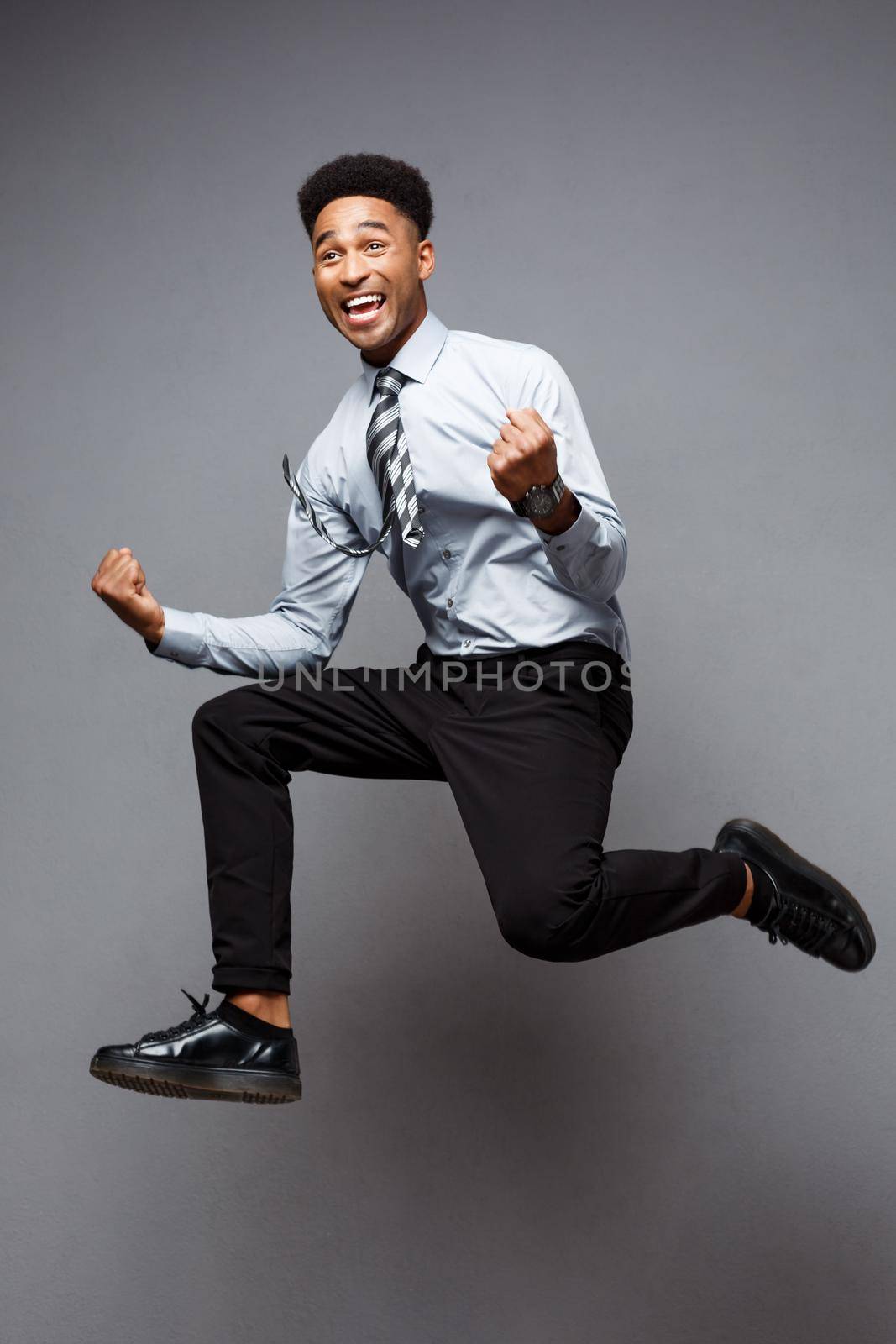 Business Concept - Full length portrait of successful african american businessman happy jumping in the office