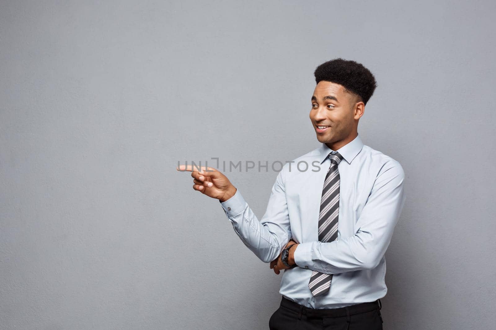 Business Concept - Confident thoughtful young African American pointing finger on side over grey background. by Benzoix