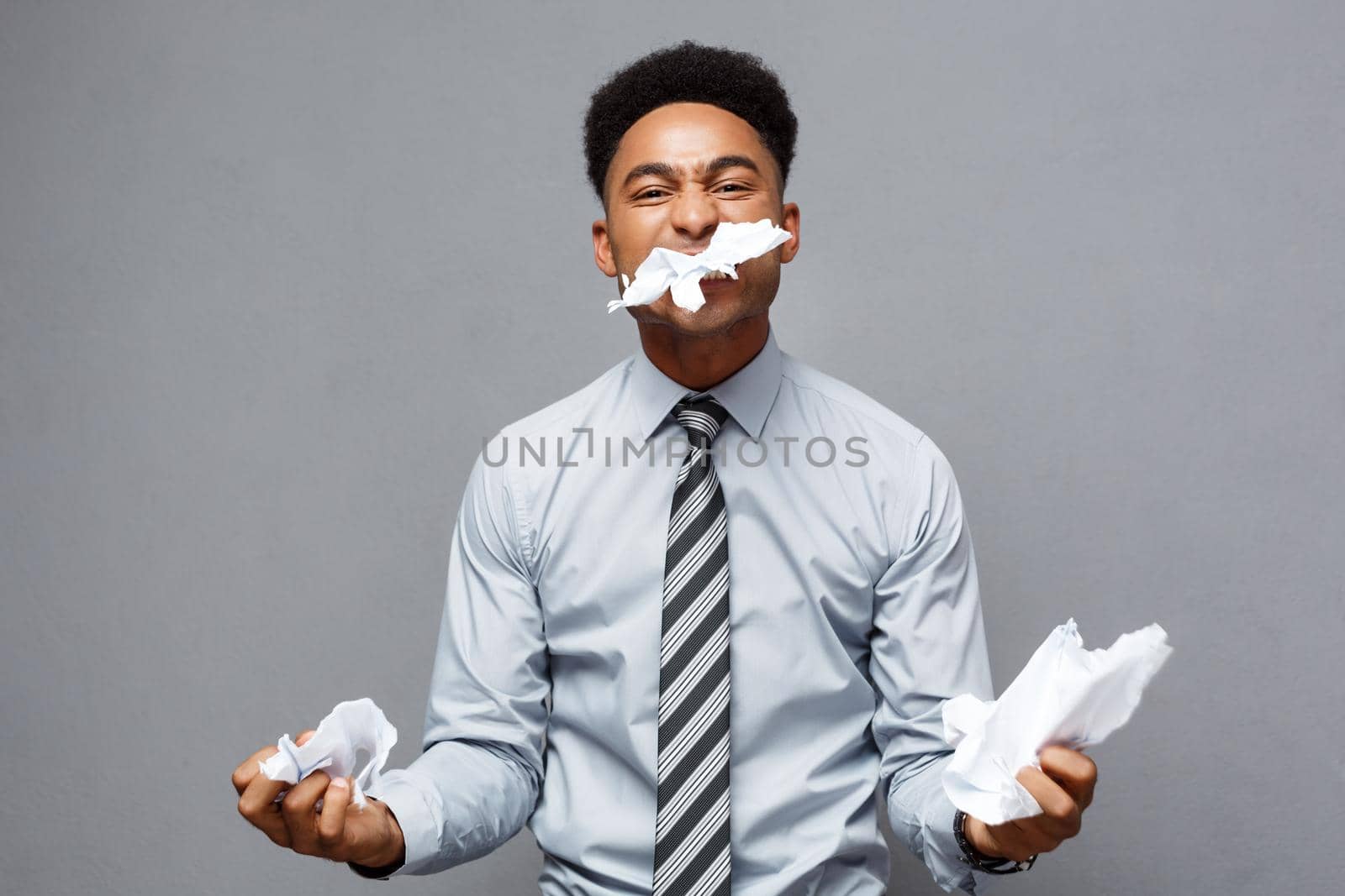 Business Concept - Young angry African American businessman while eating balled report paper. Unsuccessful Project. by Benzoix