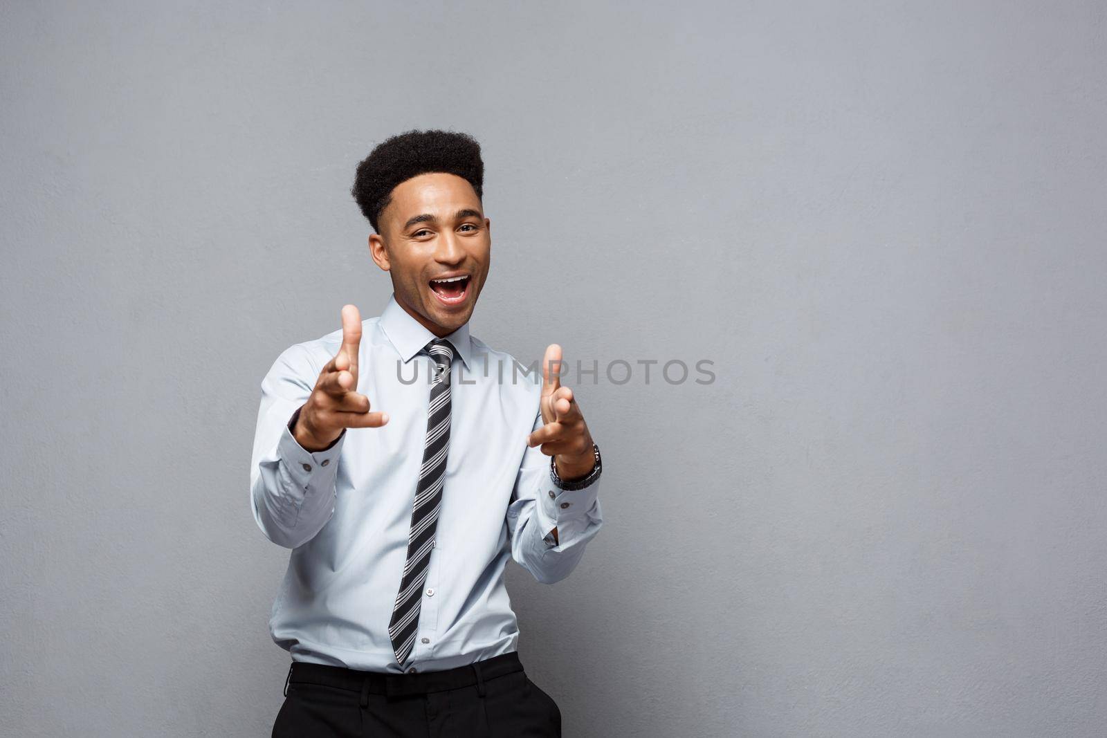 Business Concept - Cheerful happy young African American holding gun sign with fingers pointing to other