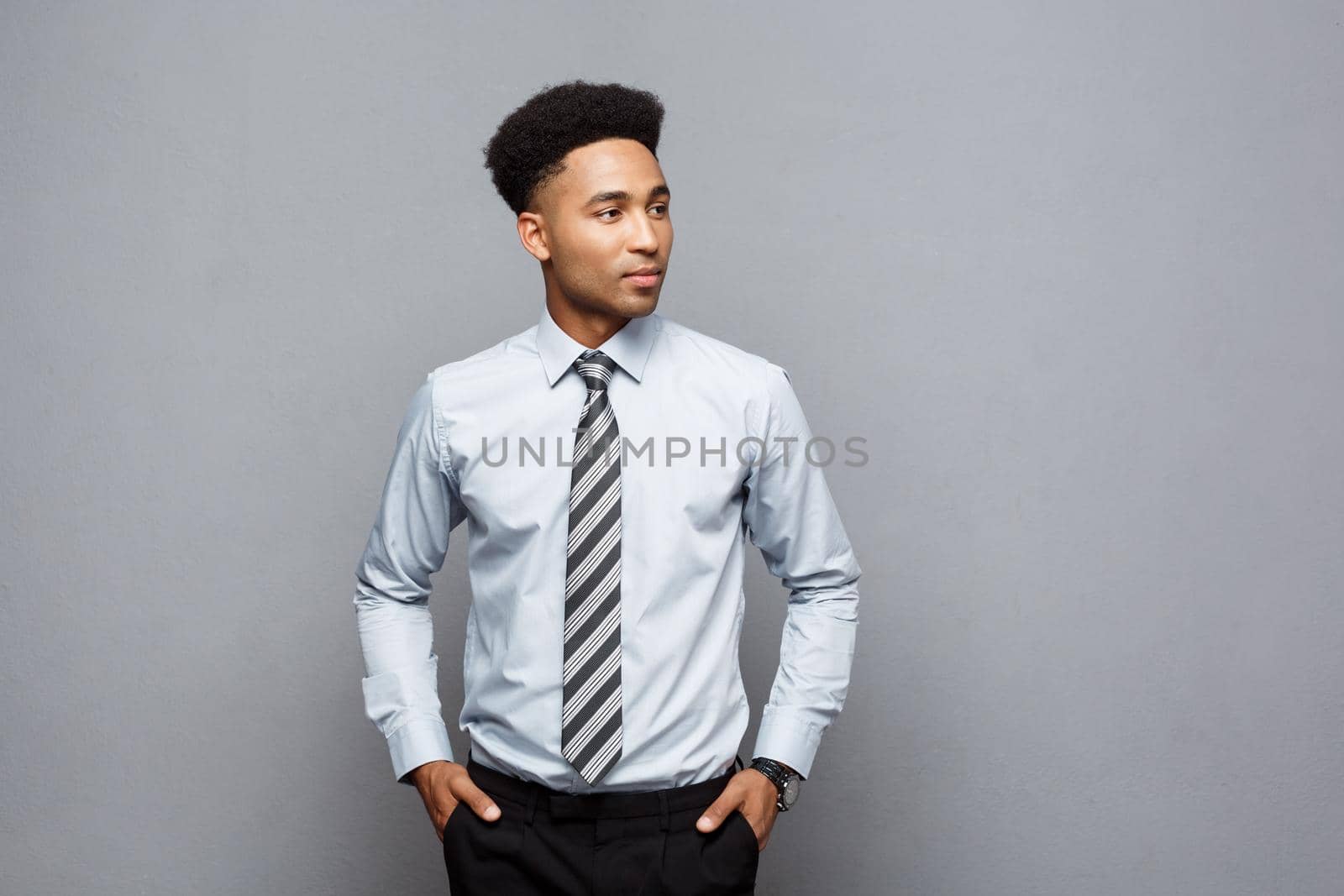 Business Concept - Happy confident professional african american businessman posing over grey background. by Benzoix