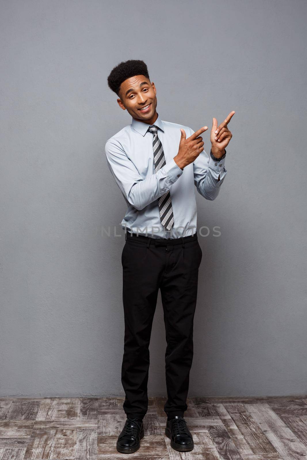 Business Concept - Full length portrait of confident african american businessman in the office pointing finger.