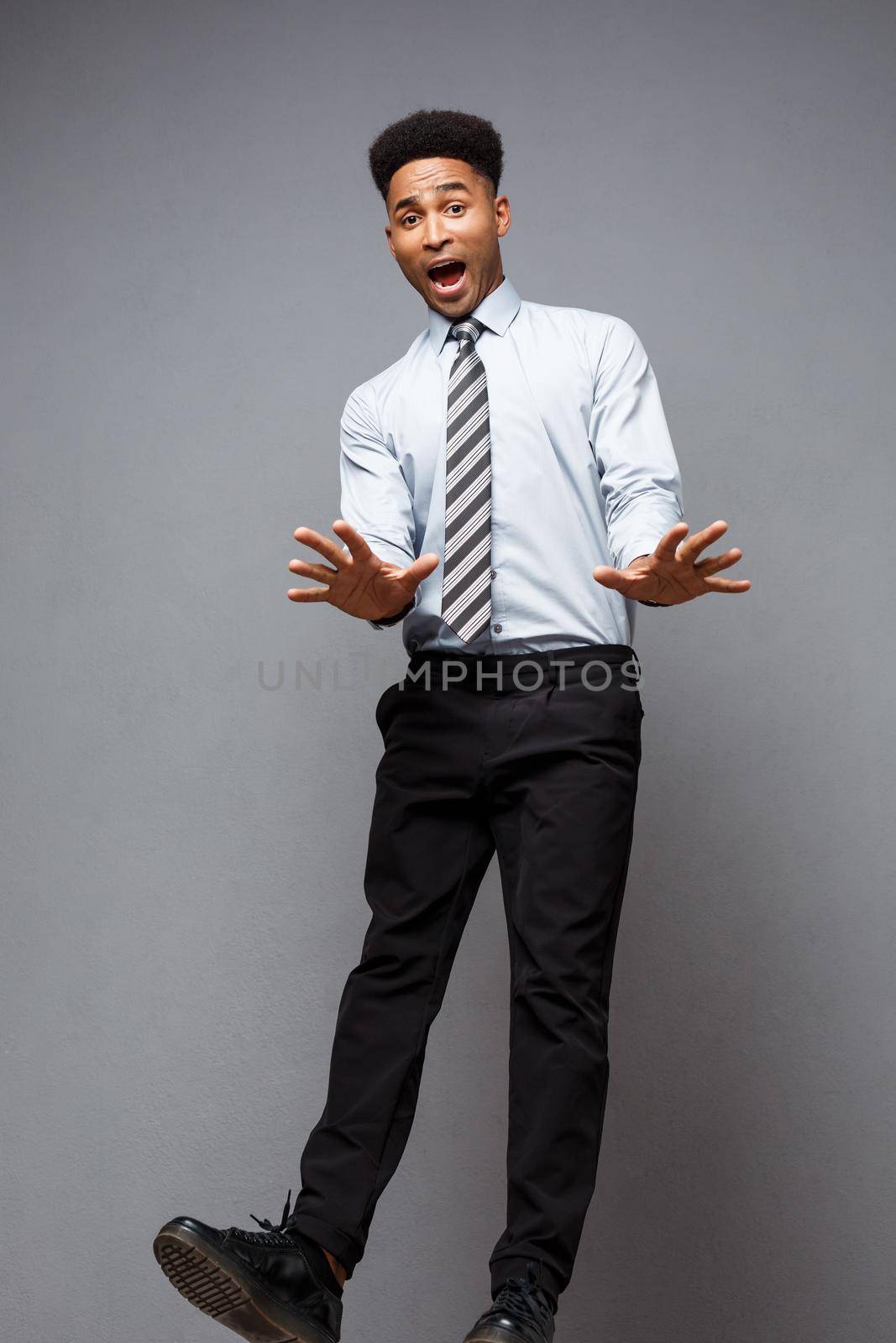 Business Concept - Full length portrait of successful african american businessman surprising jump in the office