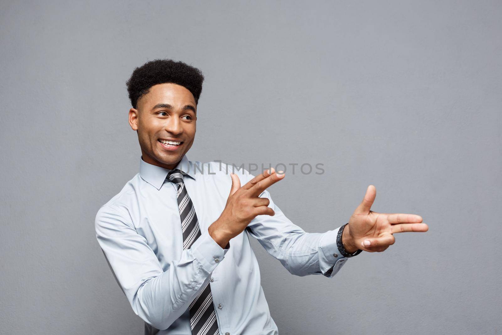 Business Concept - Cheerful happy young African American holding gun sign with fingers pointing to other. by Benzoix