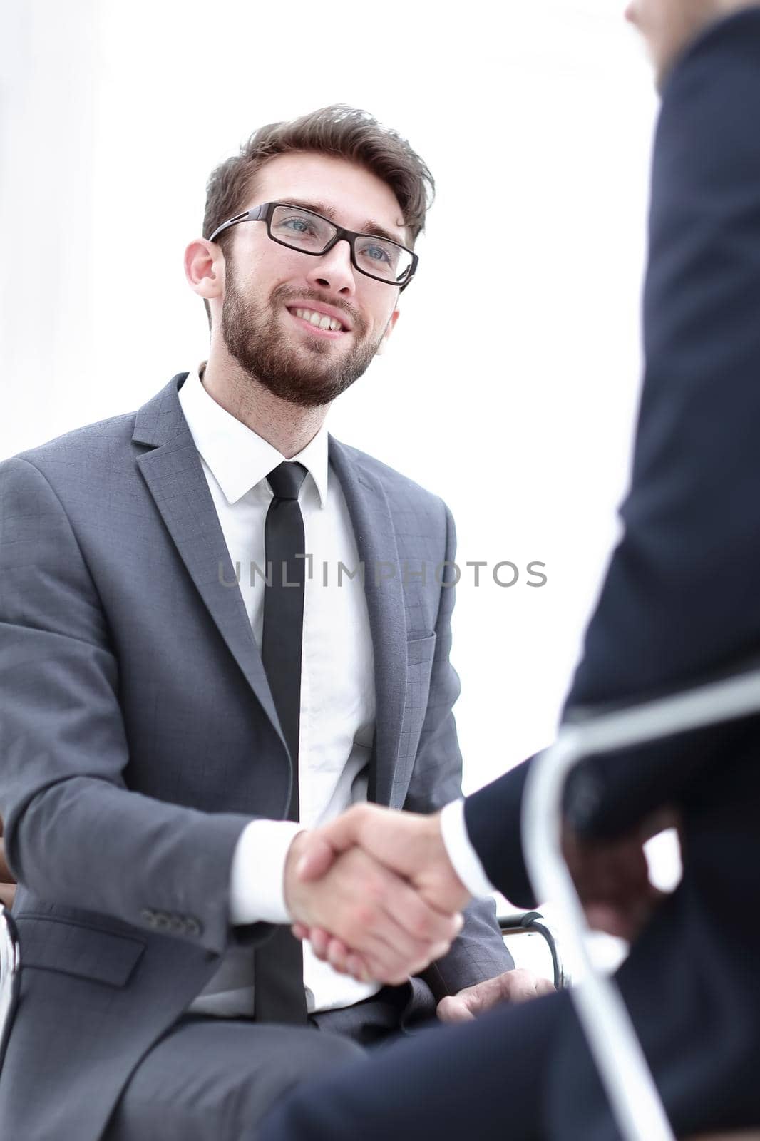 Image of two young businessmen interacting at meeting in office