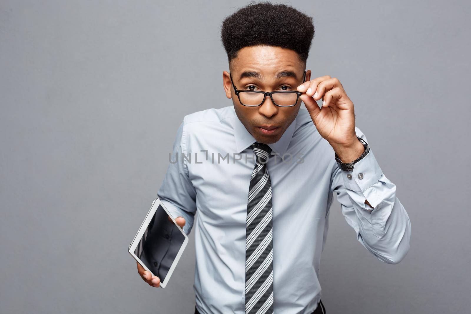Business Concept - Happy handsome professional african american businessman holding tablet with surprising facial expression