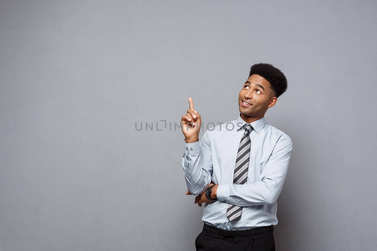 Business Concept - Confident thoughtful young African American pointing finger on side over grey background. by Benzoix