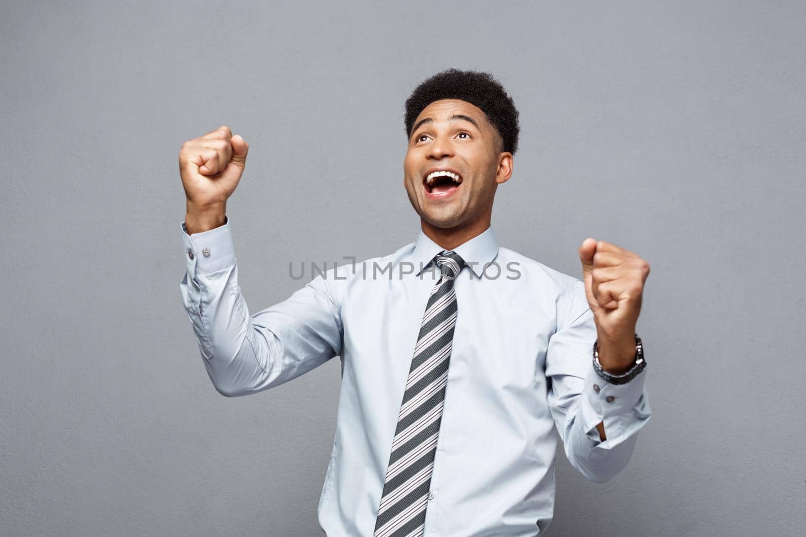 Business Concept - Confident happy young African American throwing fists in air celebrating for success projects