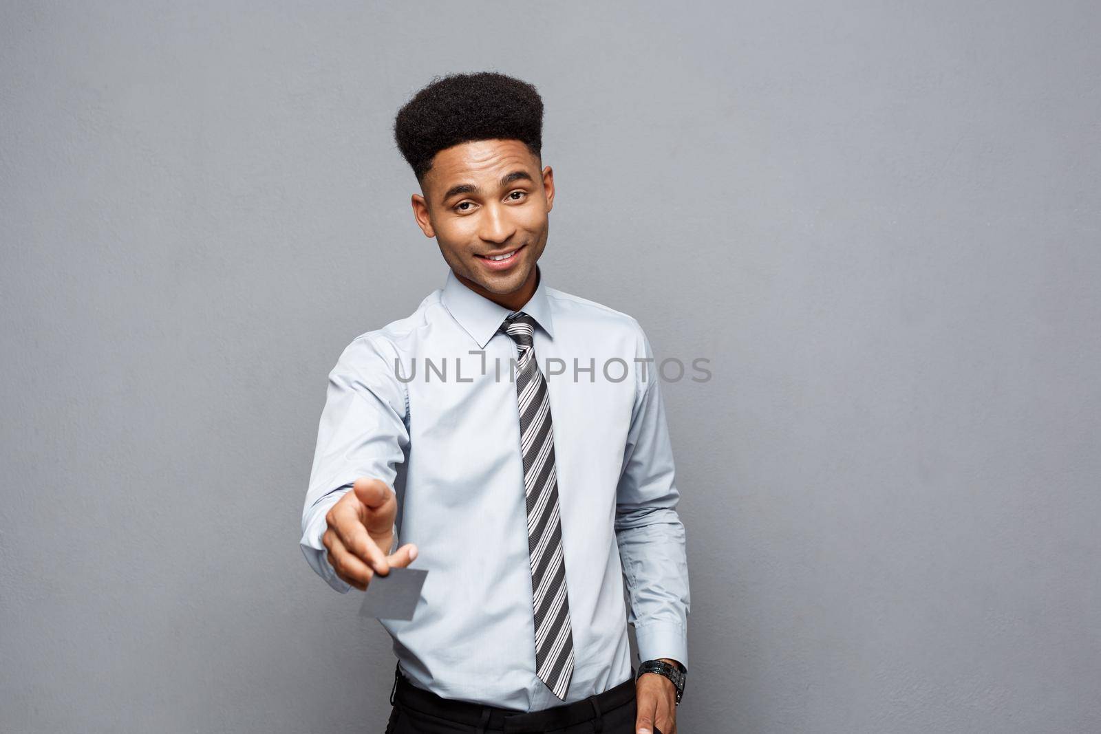 Business Concept - Happy handsome professional african american businessman giving name card to client