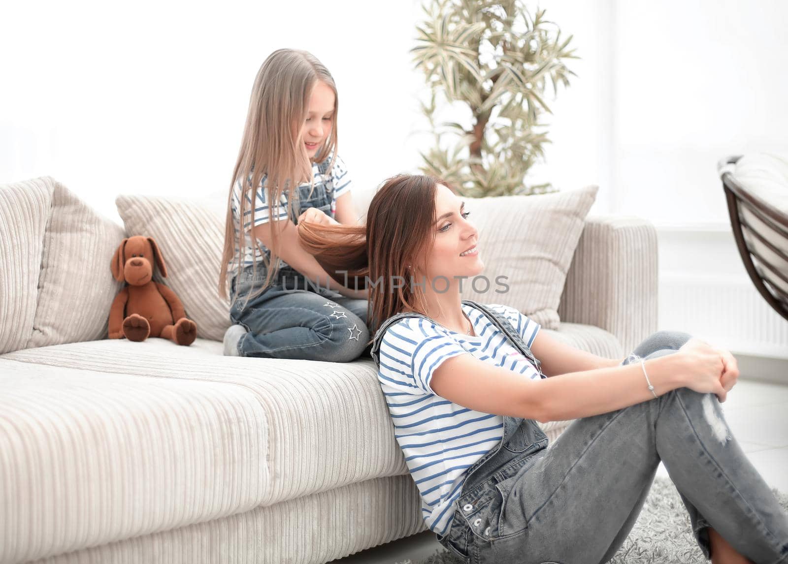 little girl makes a fashionable hairstyle of his mother.a day of beauty