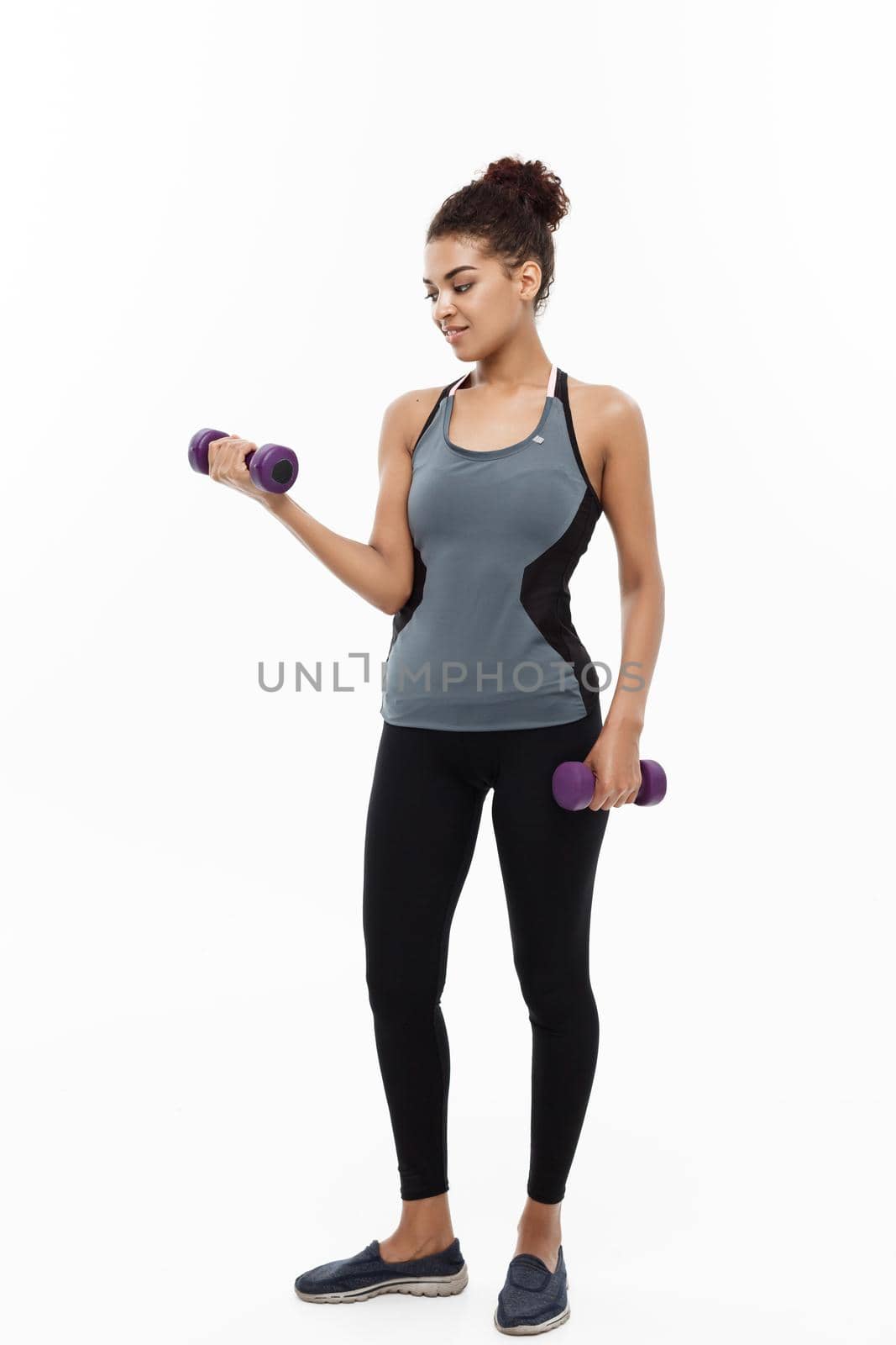 Healthy and Fitness concept - Full-length of portrait Beautiful American African lady in grey fitness clothes workout with dumbbell. Isolated on white background. by Benzoix