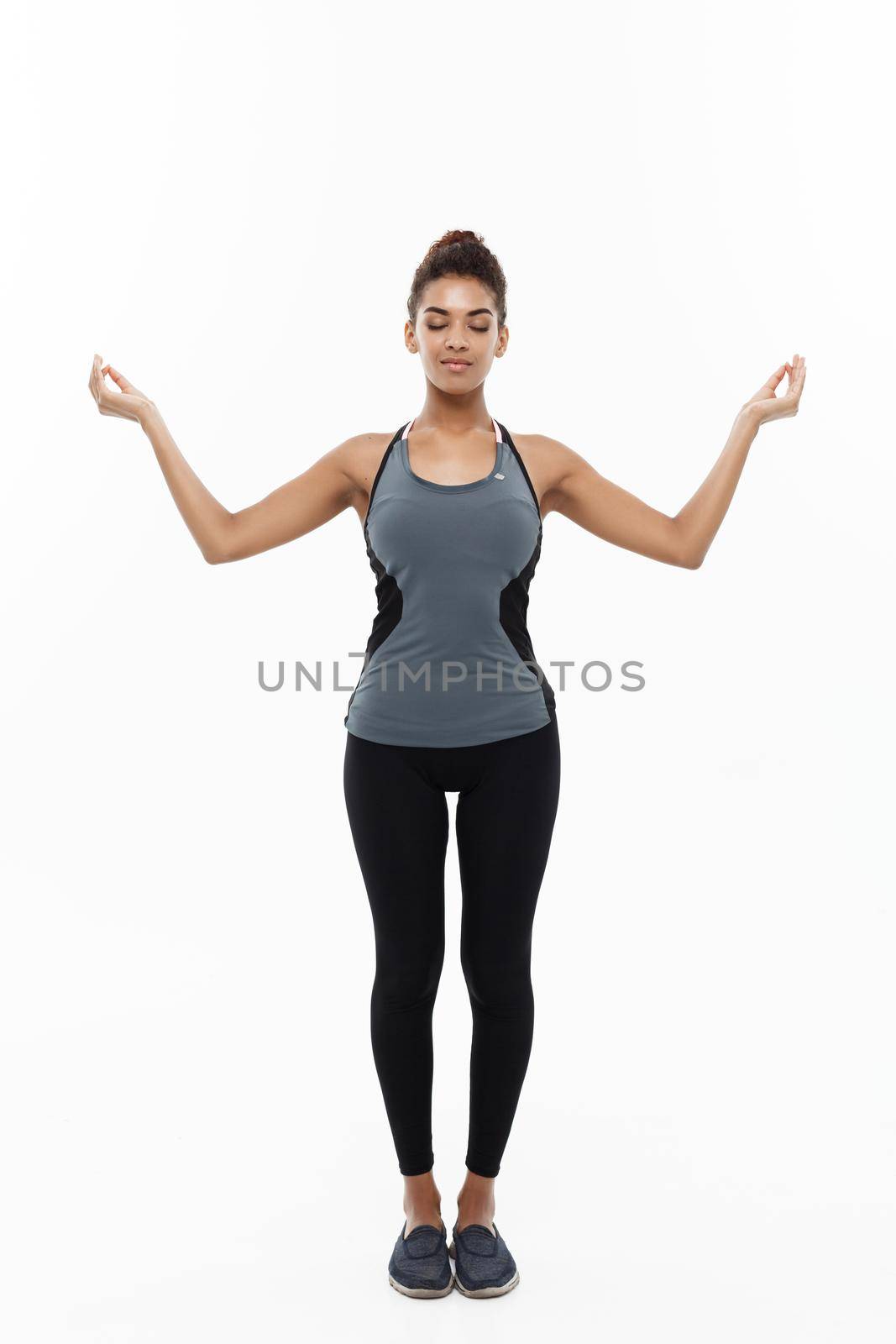 Healthy and Fitness concept - Beautiful American African lady in fitness clothing doing yoga and meditation. Isolated on white background