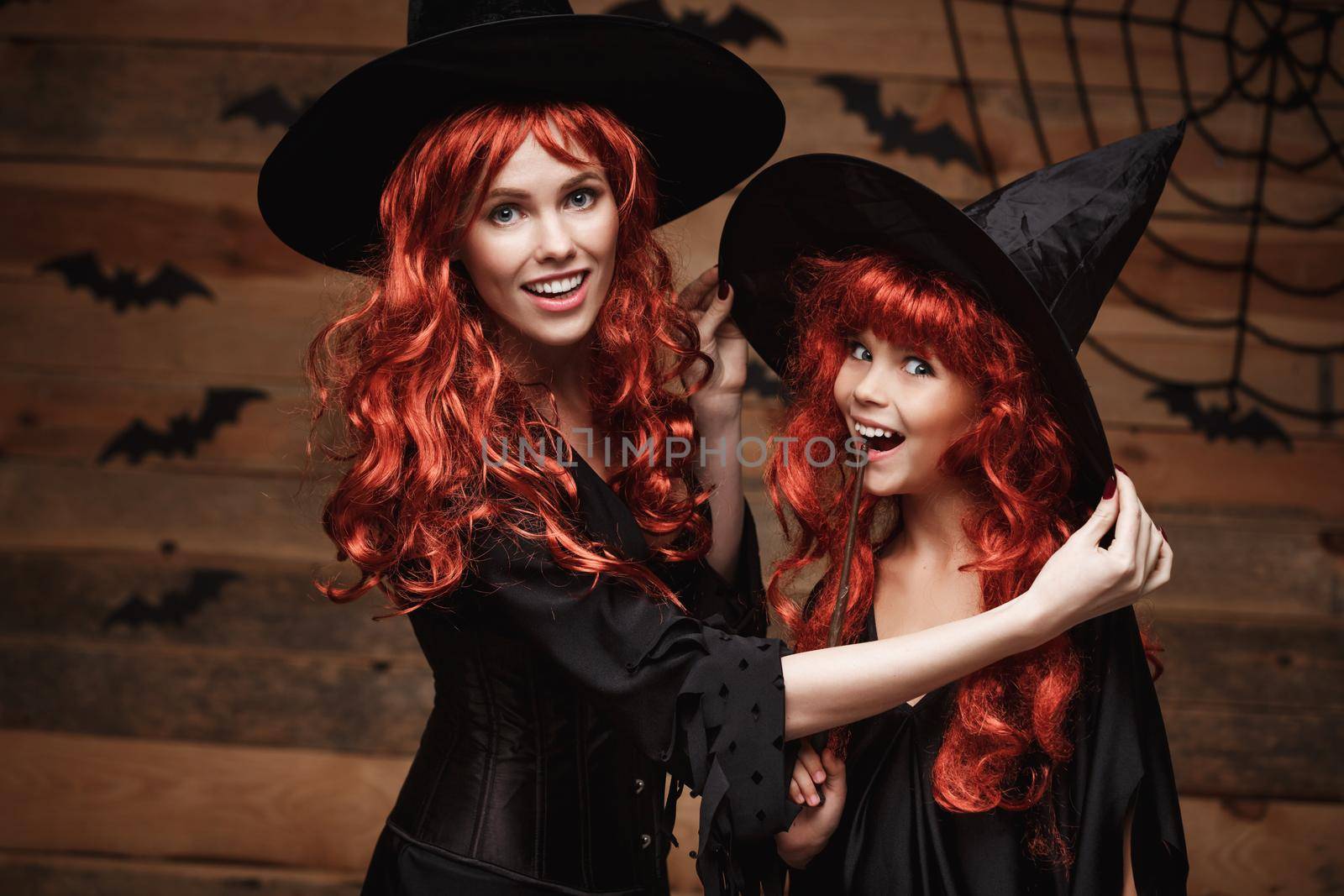 Halloween Concept - Beautiful caucasian mother dress up for her daughter in witch costumes and long curly hair ready for celebrating Halloween