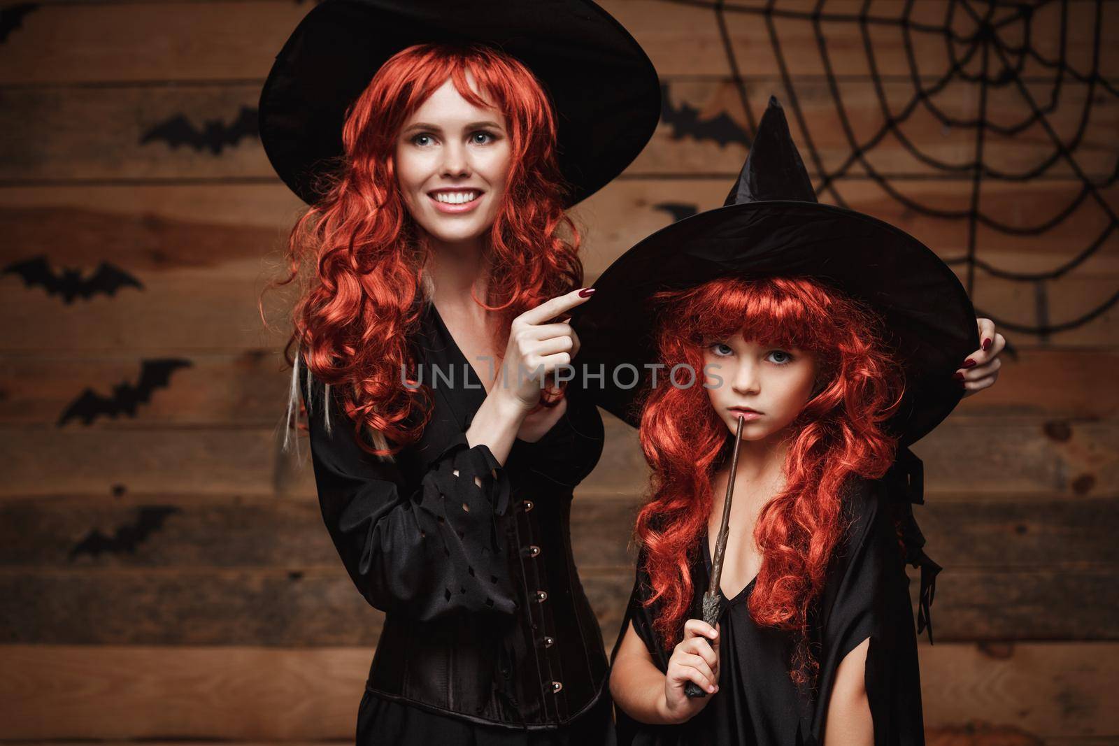 Halloween Concept - Beautiful caucasian mother dress up for her daughter in witch costumes and long curly hair ready for celebrating Halloween