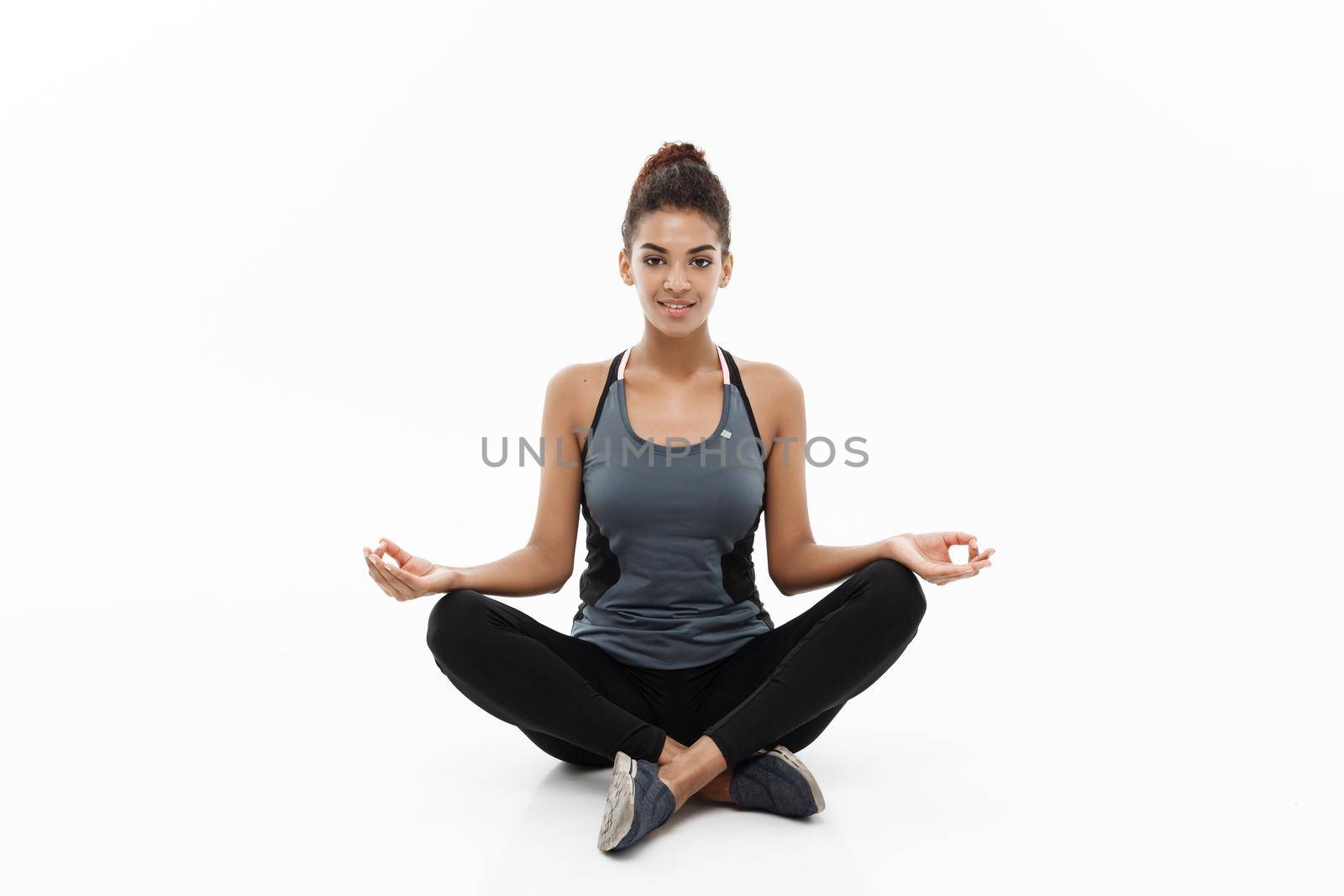 Healthy and Fitness concept - Beautiful American African lady in fitness clothing doing yoga and meditation. Isolated on white background