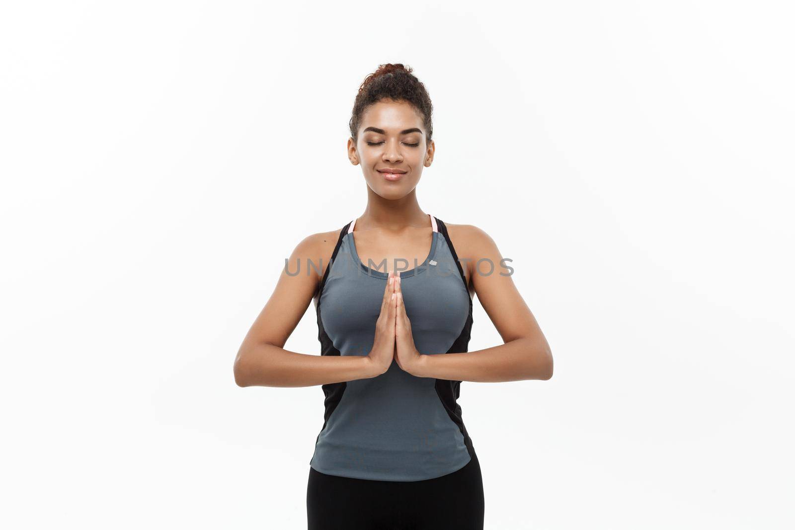 Healthy and Fitness concept - Beautiful American African lady in fitness clothing doing yoga and meditation. Isolated on white background. by Benzoix