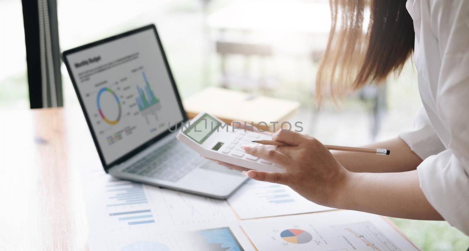Asian female accountant or banker making calculations. Savings, finances and economy concept through a laptop..